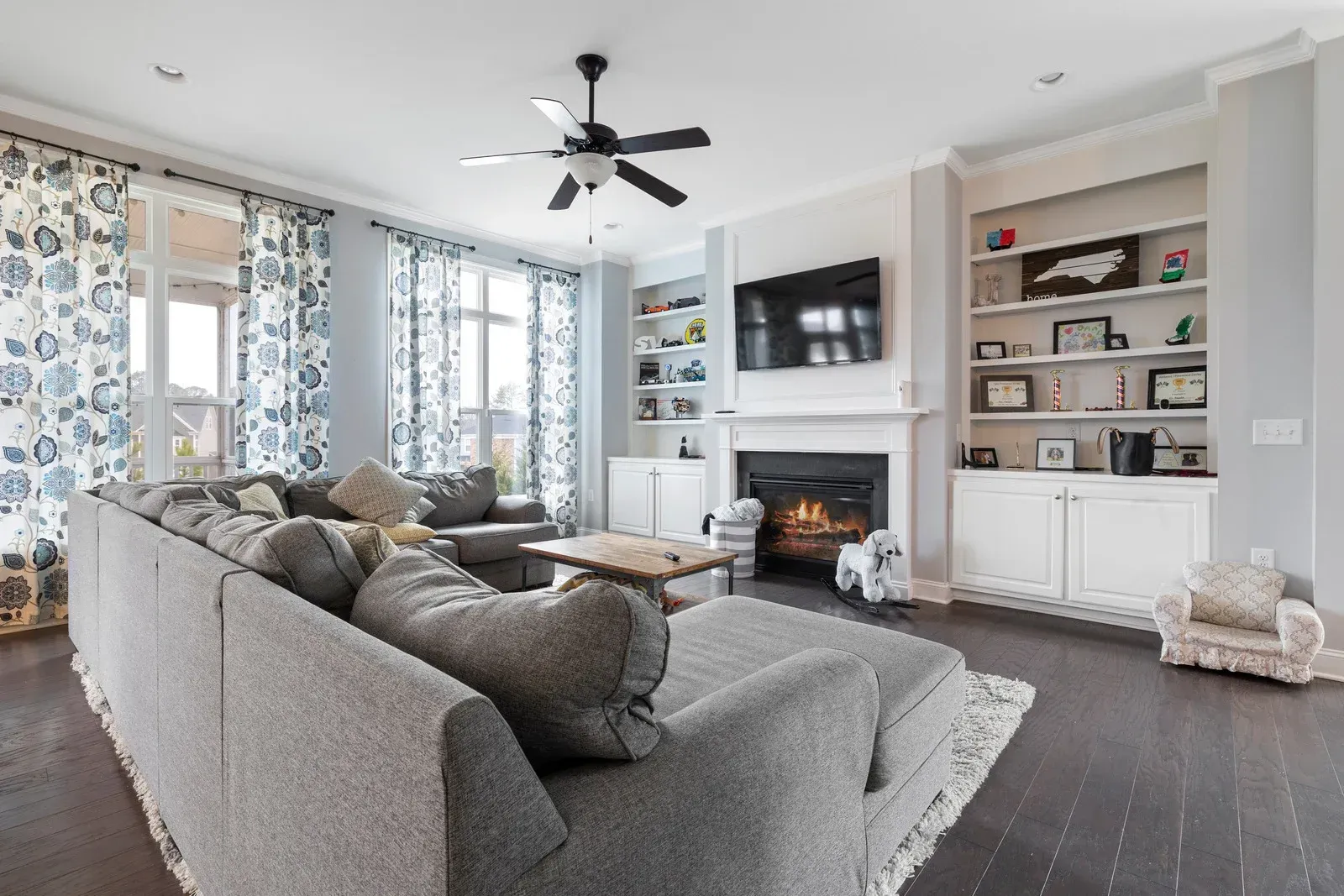 A living room with a couch , fireplace , television and ceiling fan.