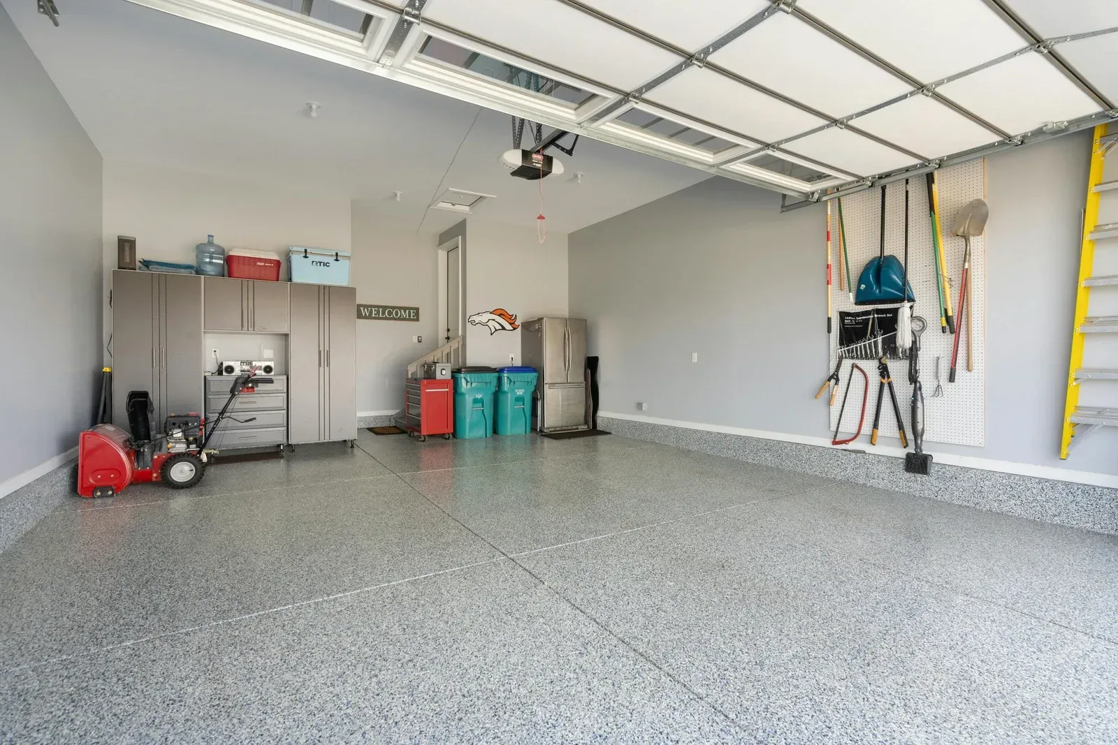 An empty garage with a snow blower and a ladder.