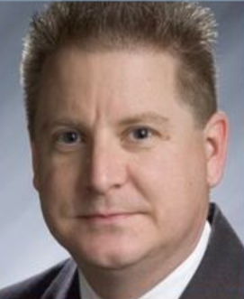 A man in a suit and tie is smiling for the camera.