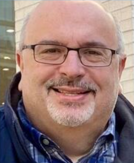 A man with glasses and a beard is smiling for the camera.