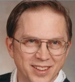 A man wearing glasses is smiling for the camera.