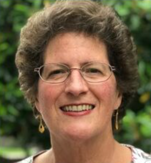 A woman wearing glasses and earrings is smiling for the camera.