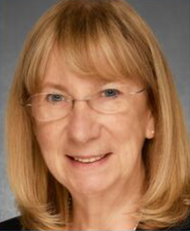 A woman with blonde hair and glasses is smiling for the camera.