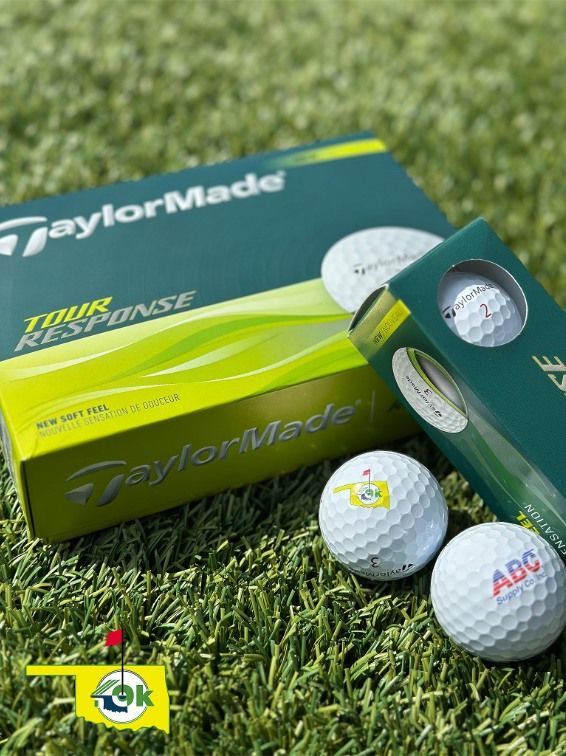 TaylorMade Tour Response golf balls and box on green grass. Two balls display logos.