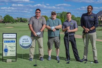 Four men pose on a golf course near a 