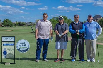 Four men pose on a golf course near a 