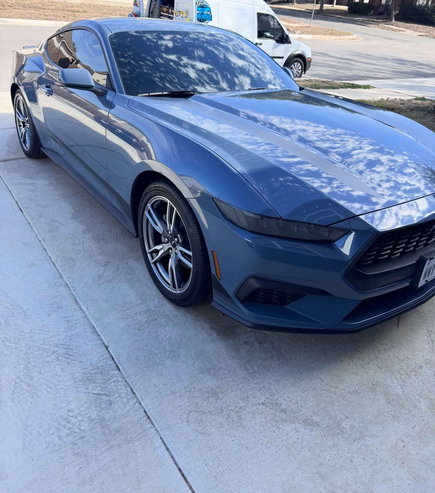 Blue Ford Mustang parked on a concrete driveway.
