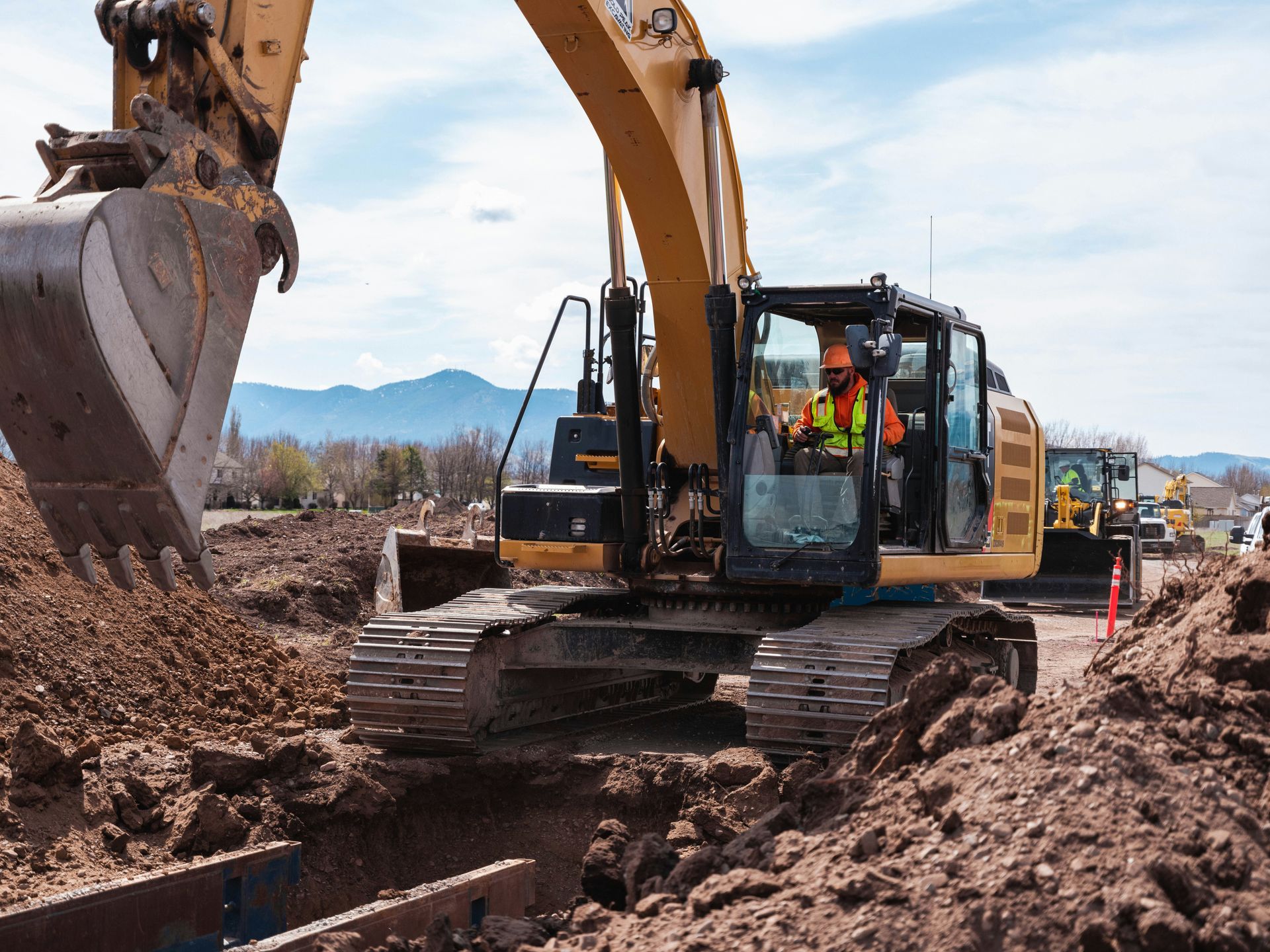 Yellow excavator digging a trench on a civil construction site.