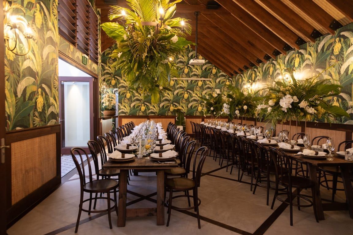 A long table with plates and chairs in a room with a chandelier hanging from the ceiling.