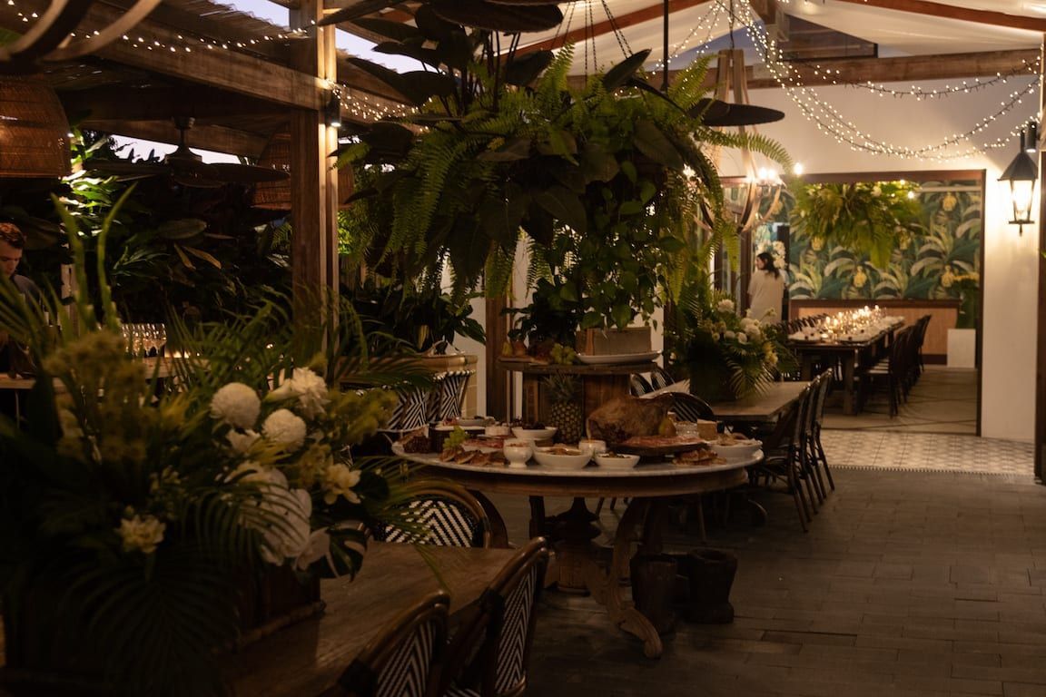 A restaurant with tables and chairs and a table with food on it.