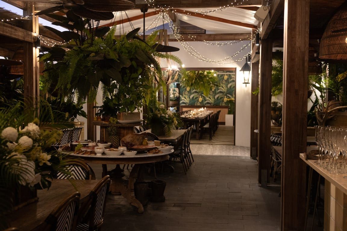 A restaurant with tables and chairs and lots of plants.