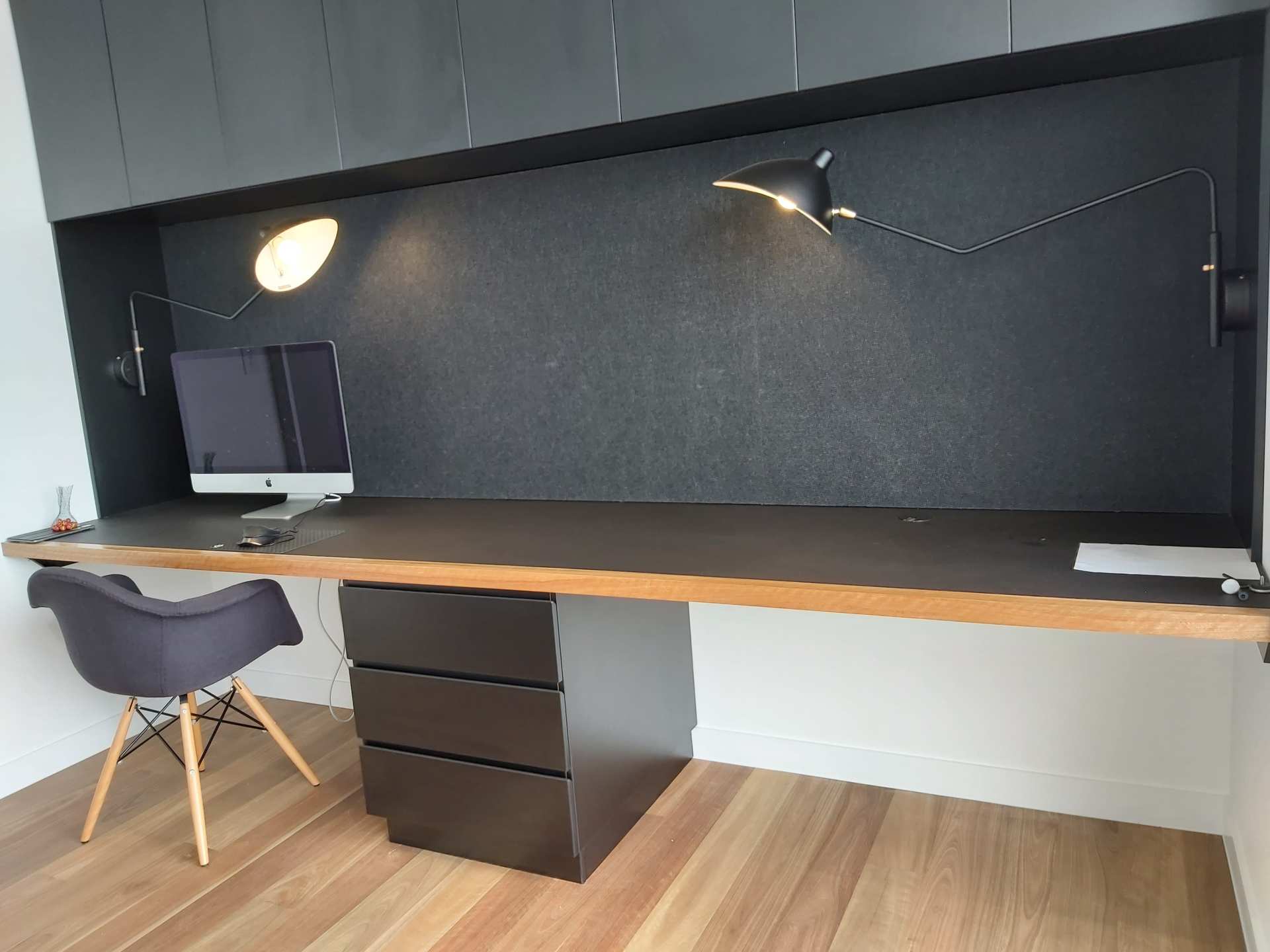 A desk with a computer on it and a chair in a room.