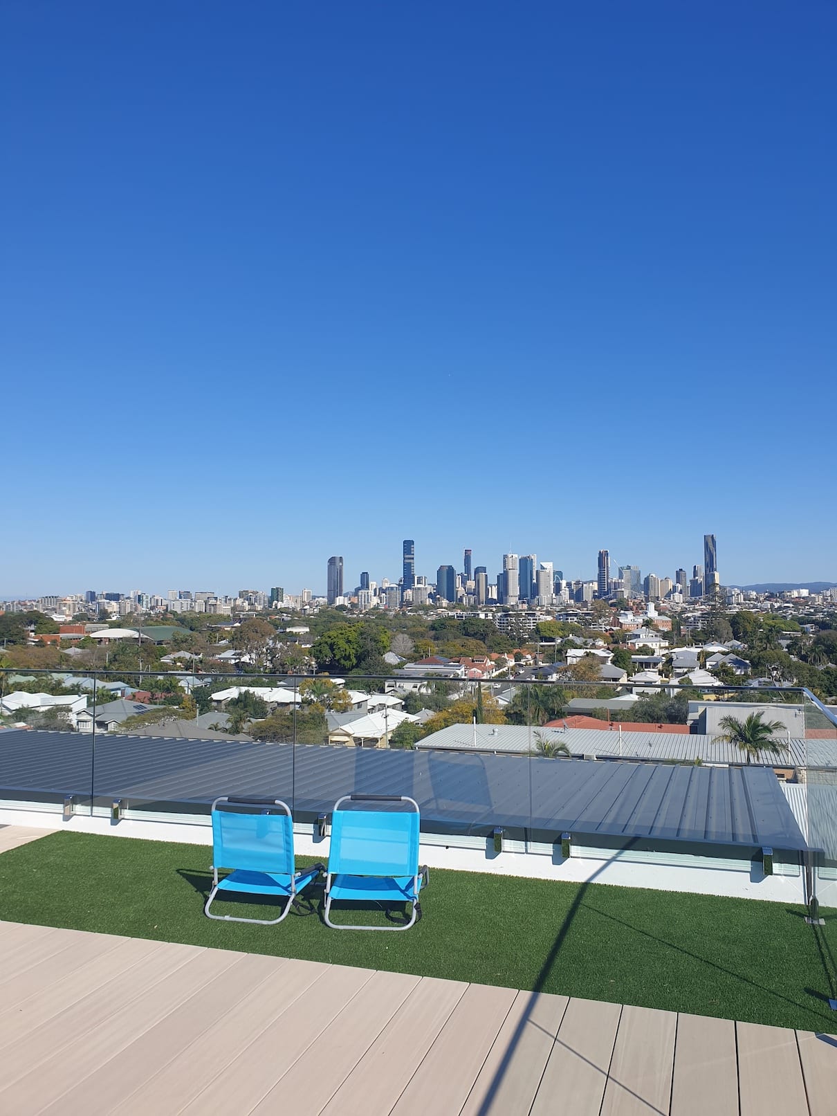 Two blue chairs on a rooftop with a city skyline in the background