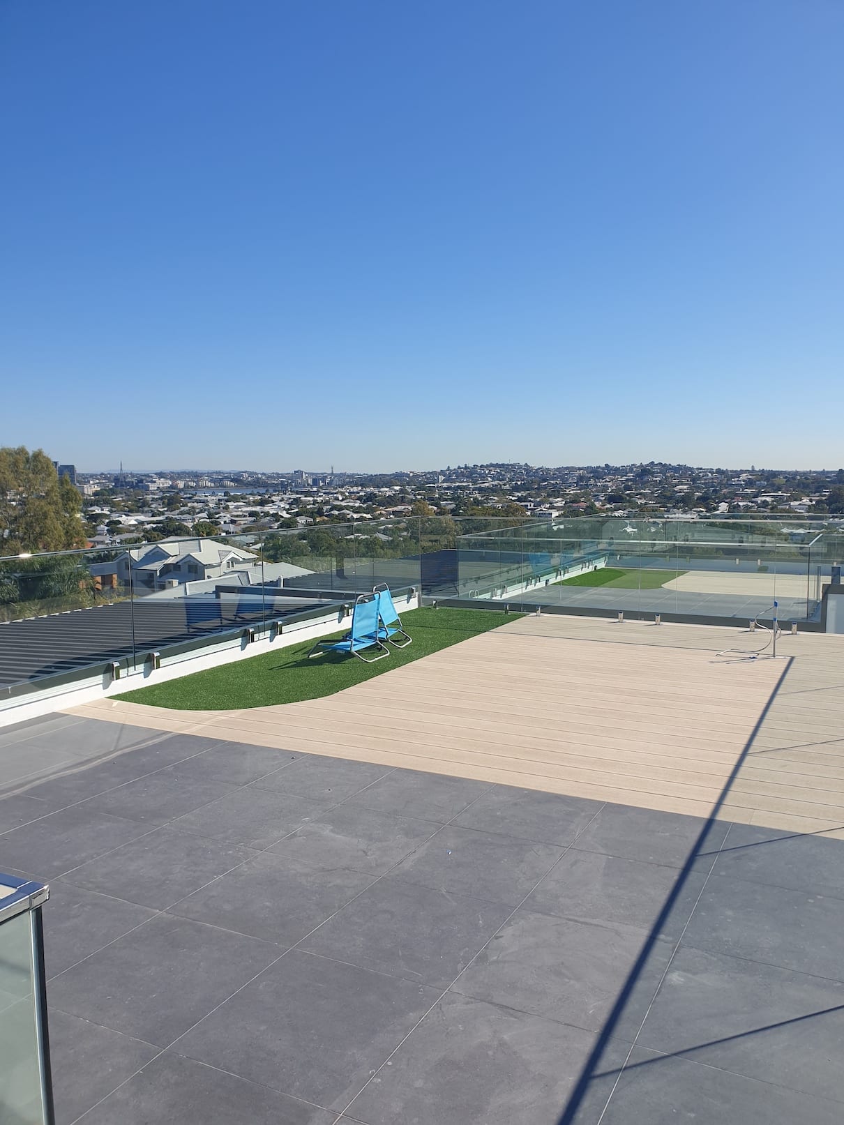 A rooftop with a view of a city and a bench.