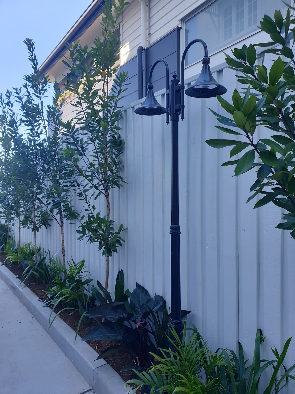A fence with trees and a street light in front of it