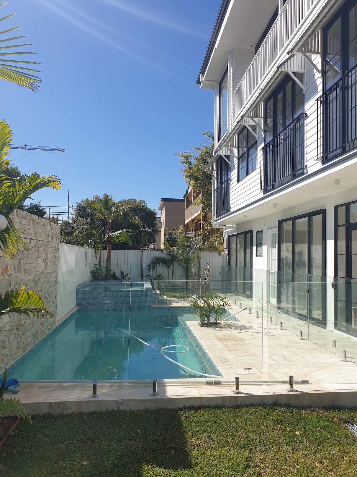 A large swimming pool is in the backyard of a house.