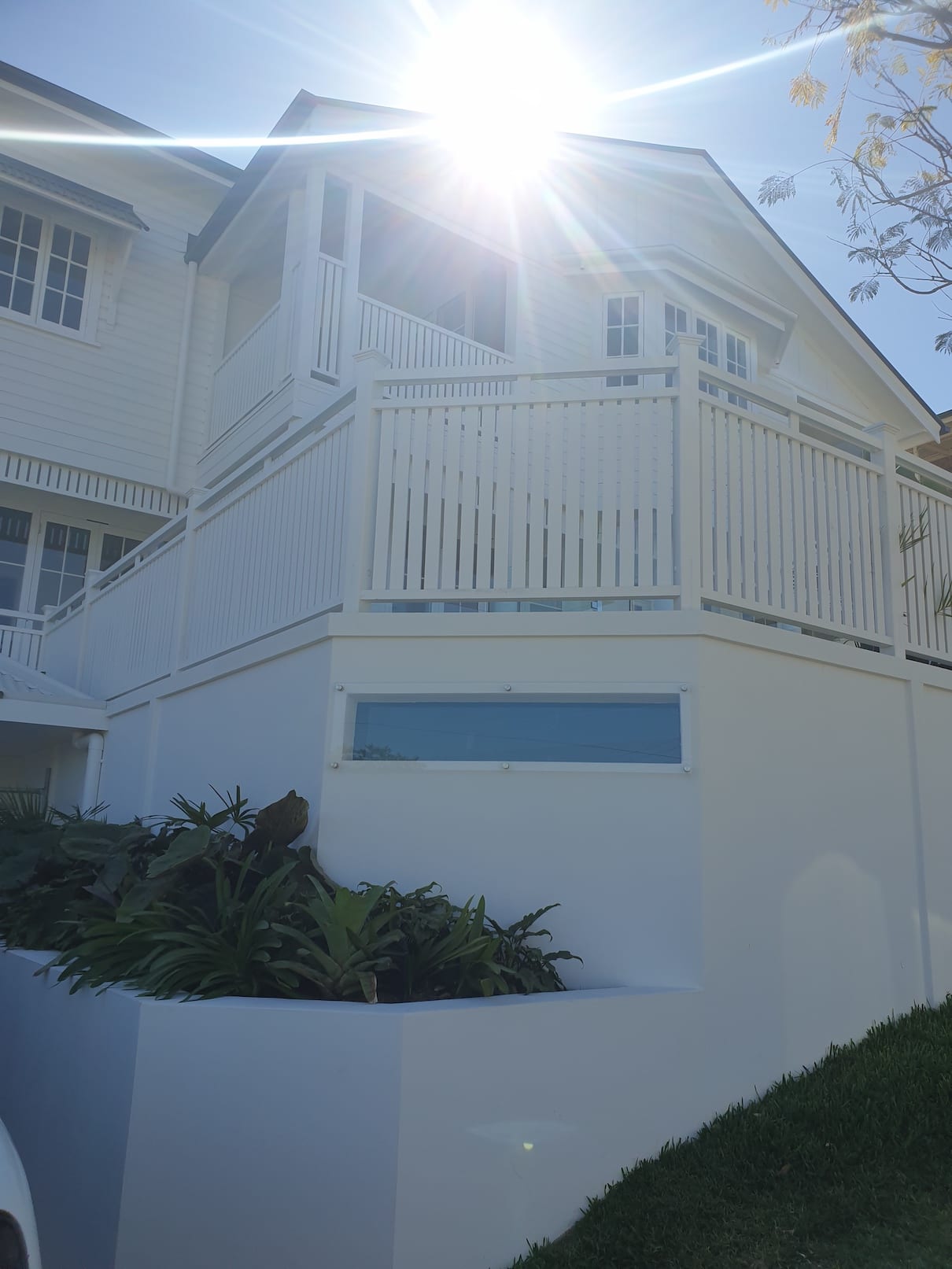 A white house with a white railing and a blue window.