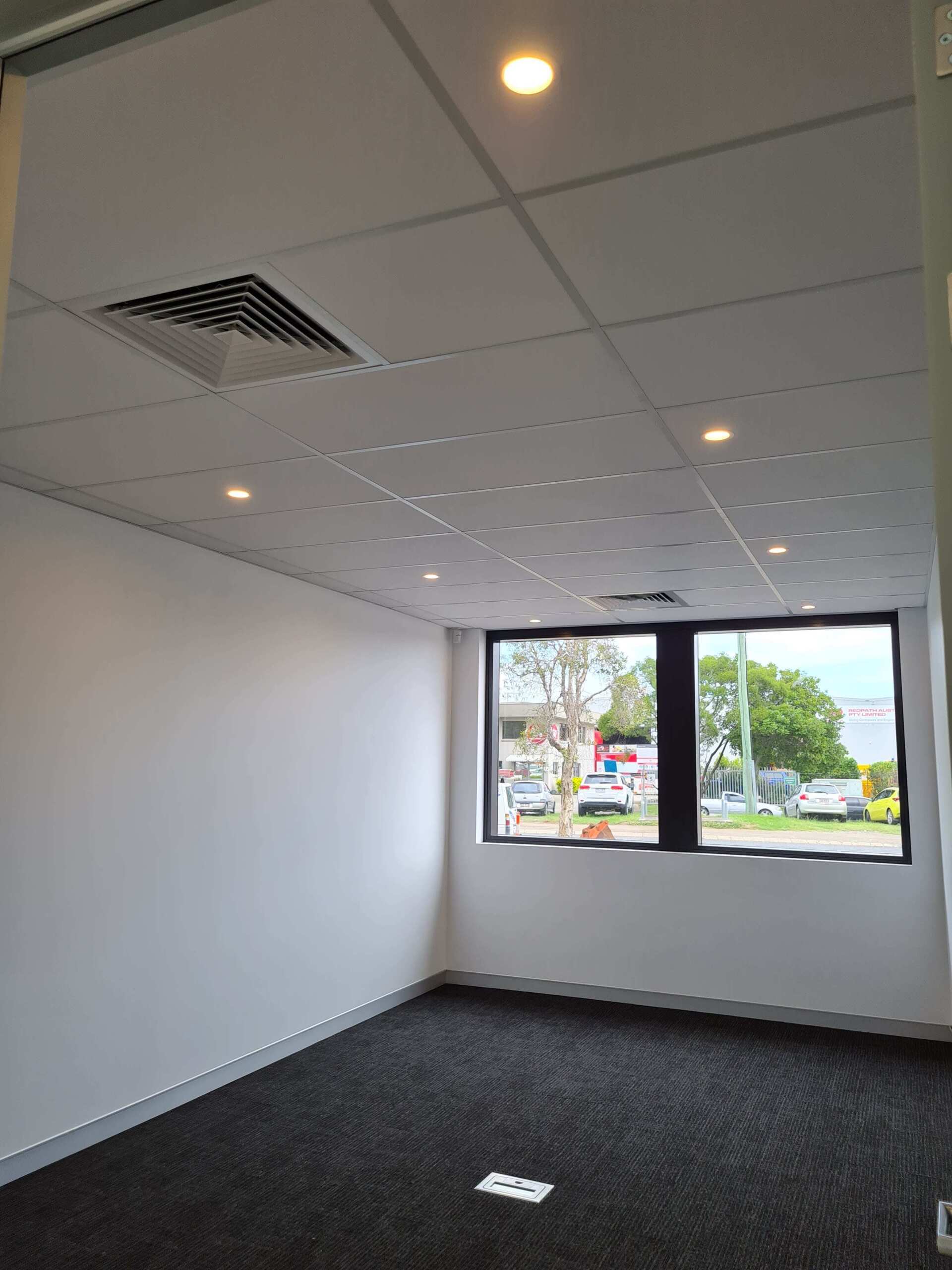 An empty room with a window and a ceiling fan.