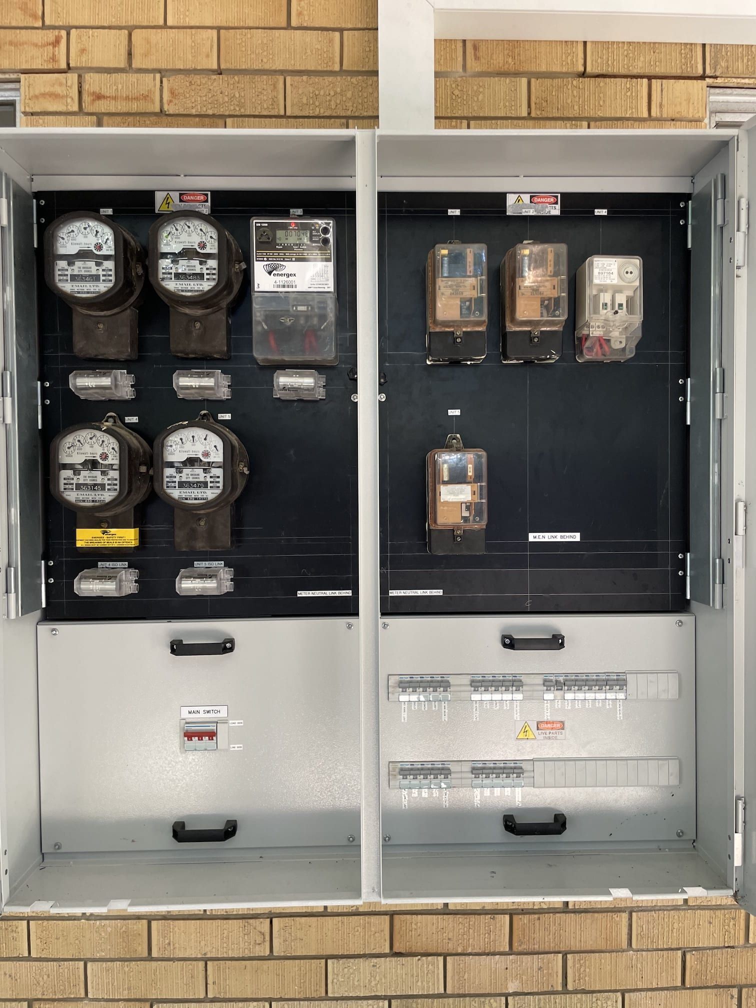A brick wall with a cabinet filled with electrical equipment and meters.