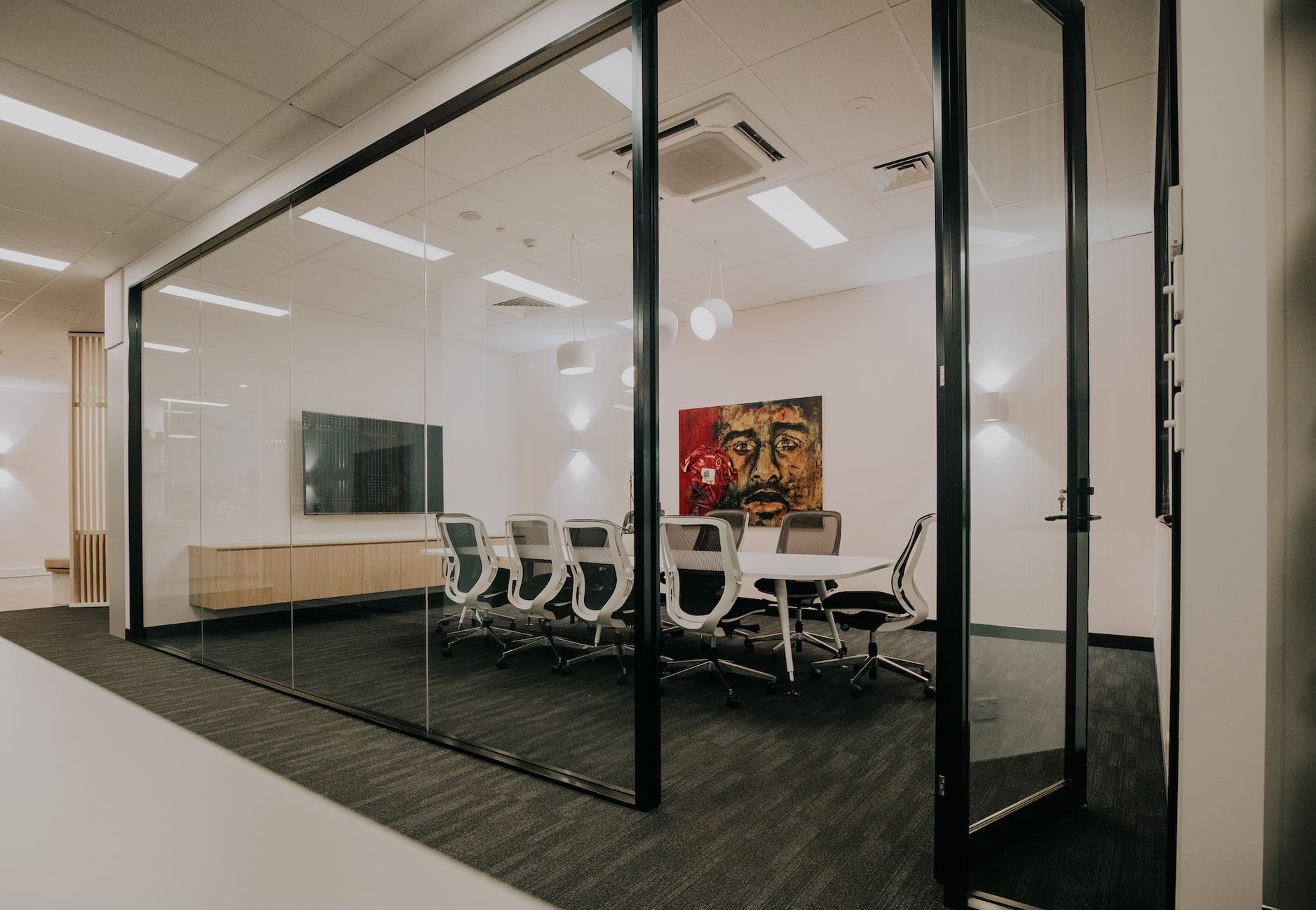 A conference room with a glass wall and a table and chairs.
