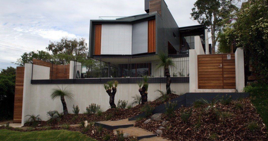 A modern house is sitting on top of a hill surrounded by trees.