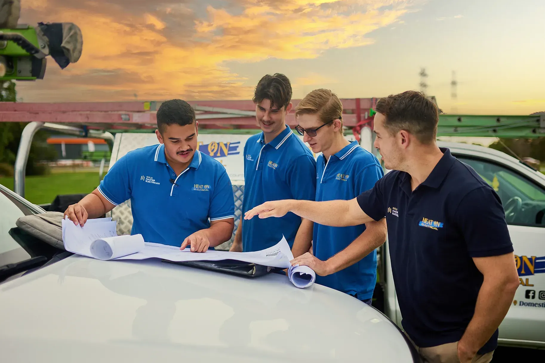 A group of men are standing around a car looking at a blueprint.