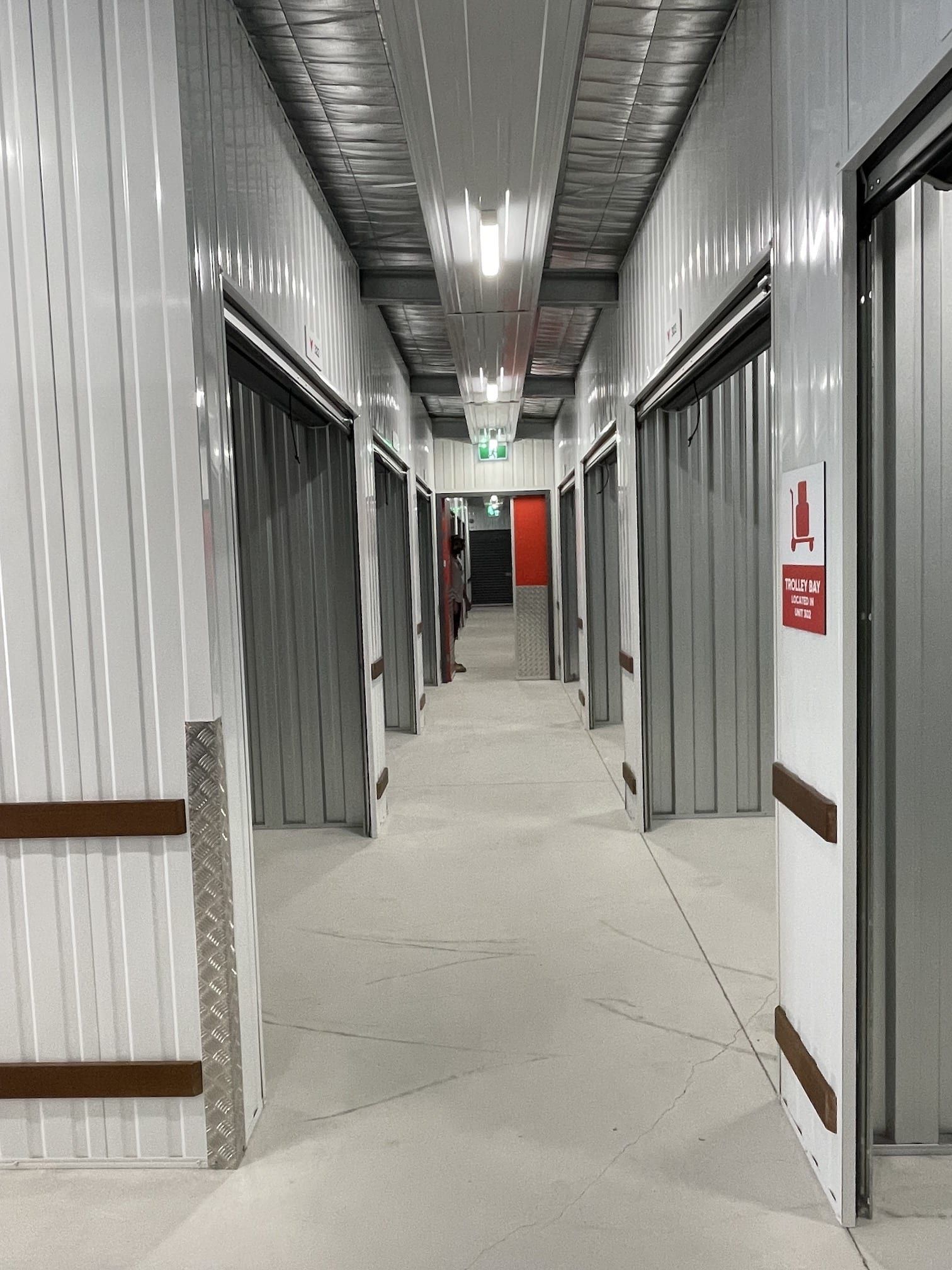 A long hallway with a fire exit sign on the wall.