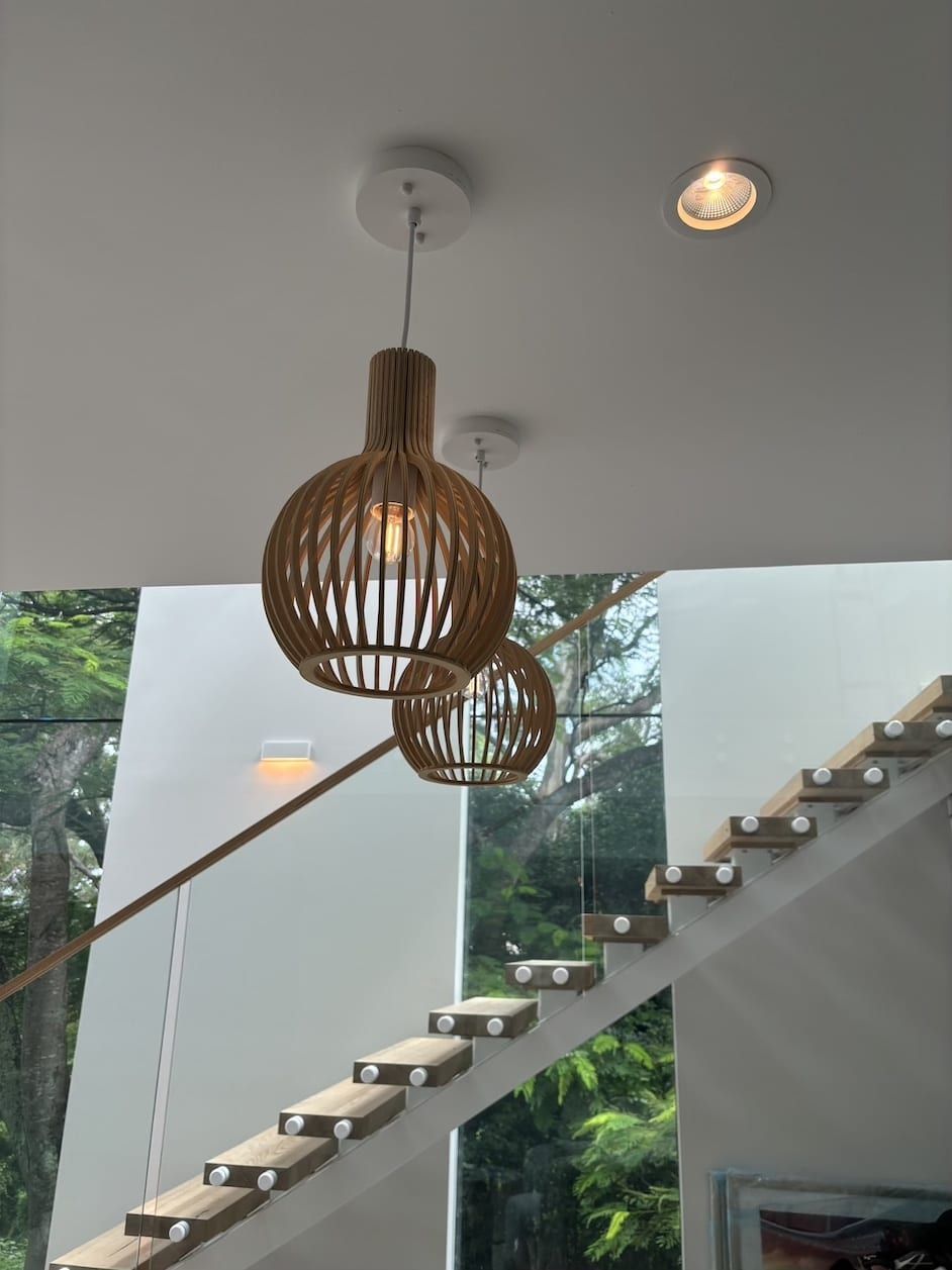 Two pendant lights are hanging from the ceiling above a wooden staircase.