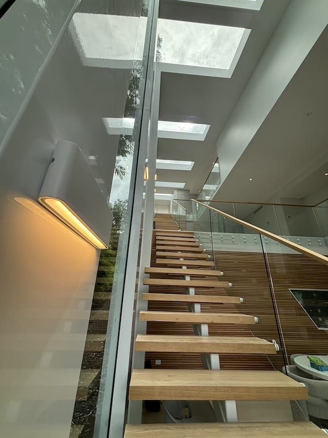 A staircase with wooden steps and a glass railing in a house.