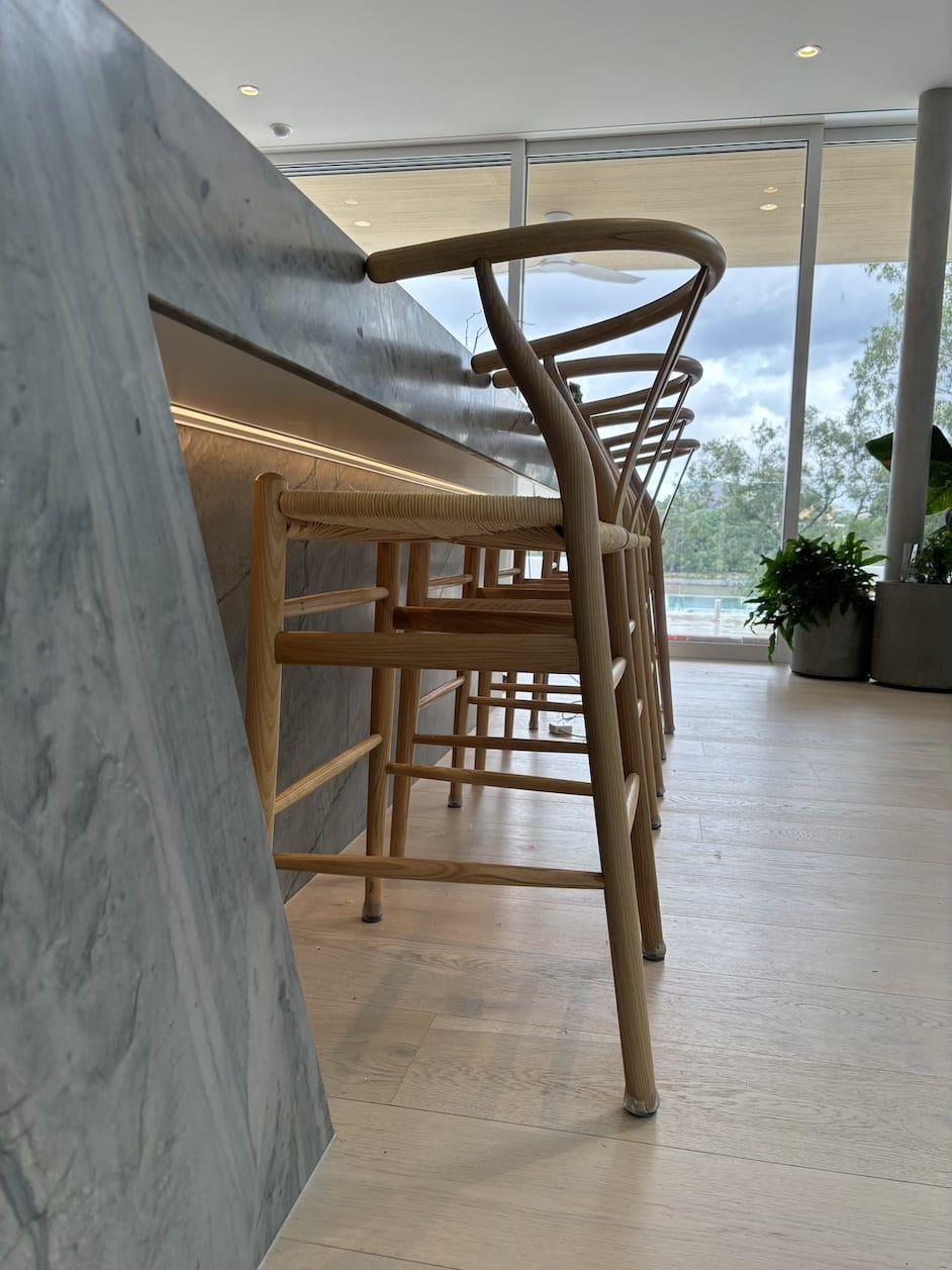 A row of wooden bar stools sitting next to a counter in a kitchen.