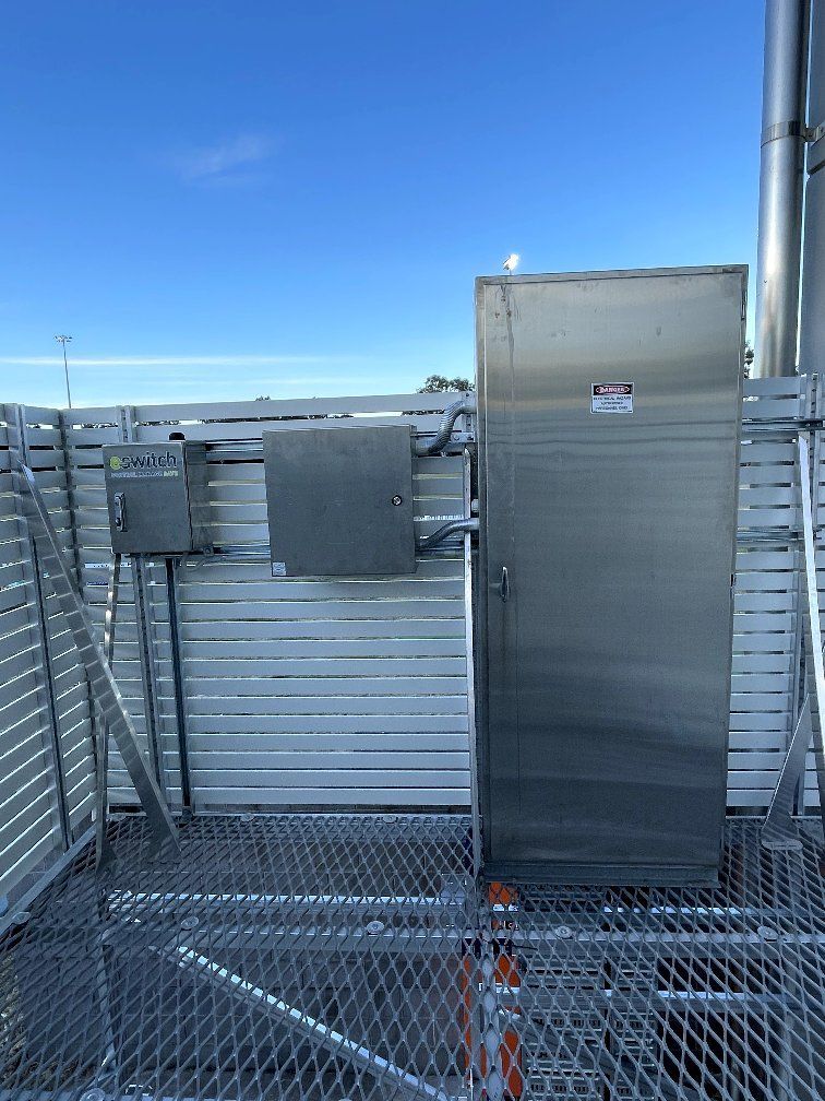 A stainless steel box is sitting on top of a metal fence.