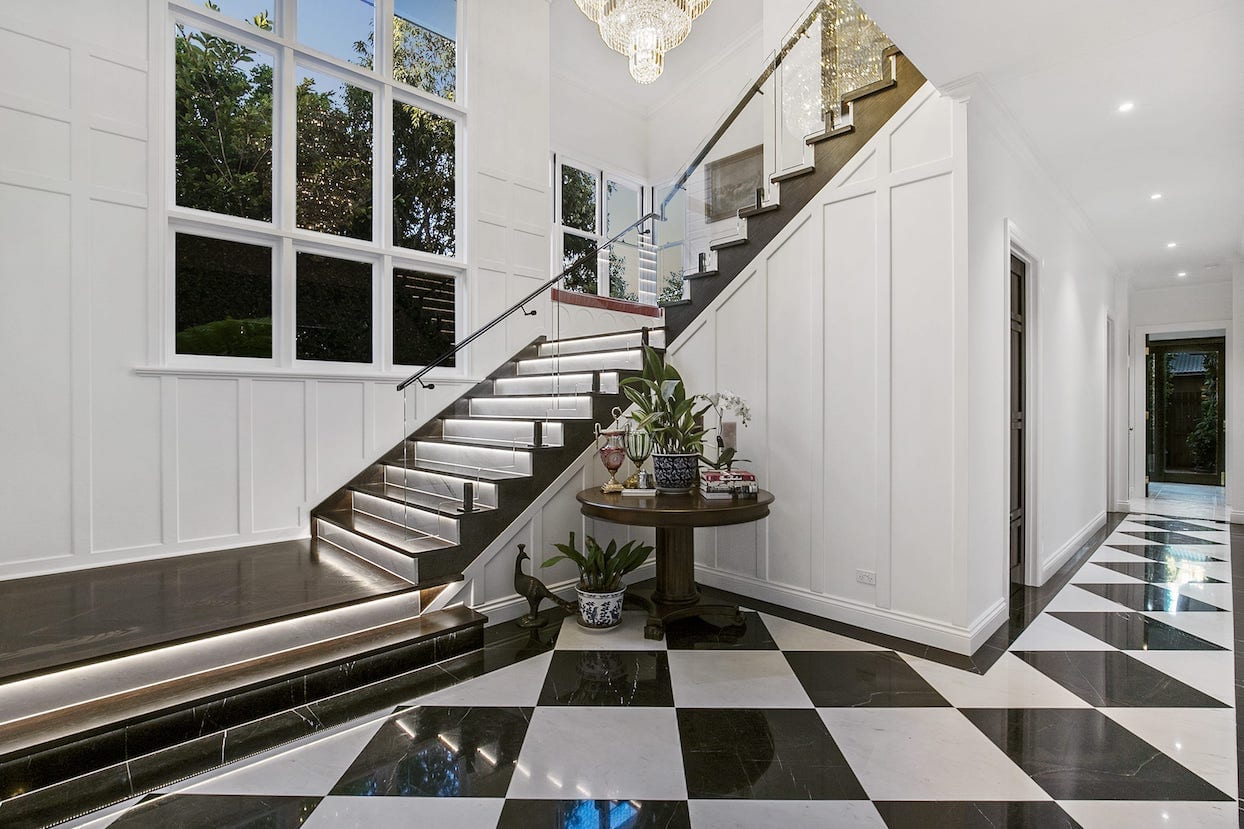 There is a staircase in the middle of the room with a checkered floor.