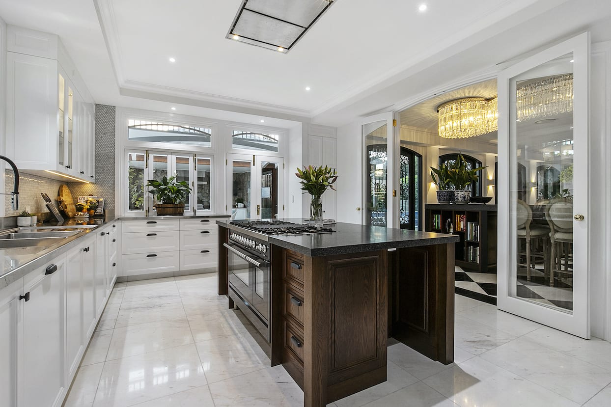 A kitchen with white cabinets and a large island in the middle.