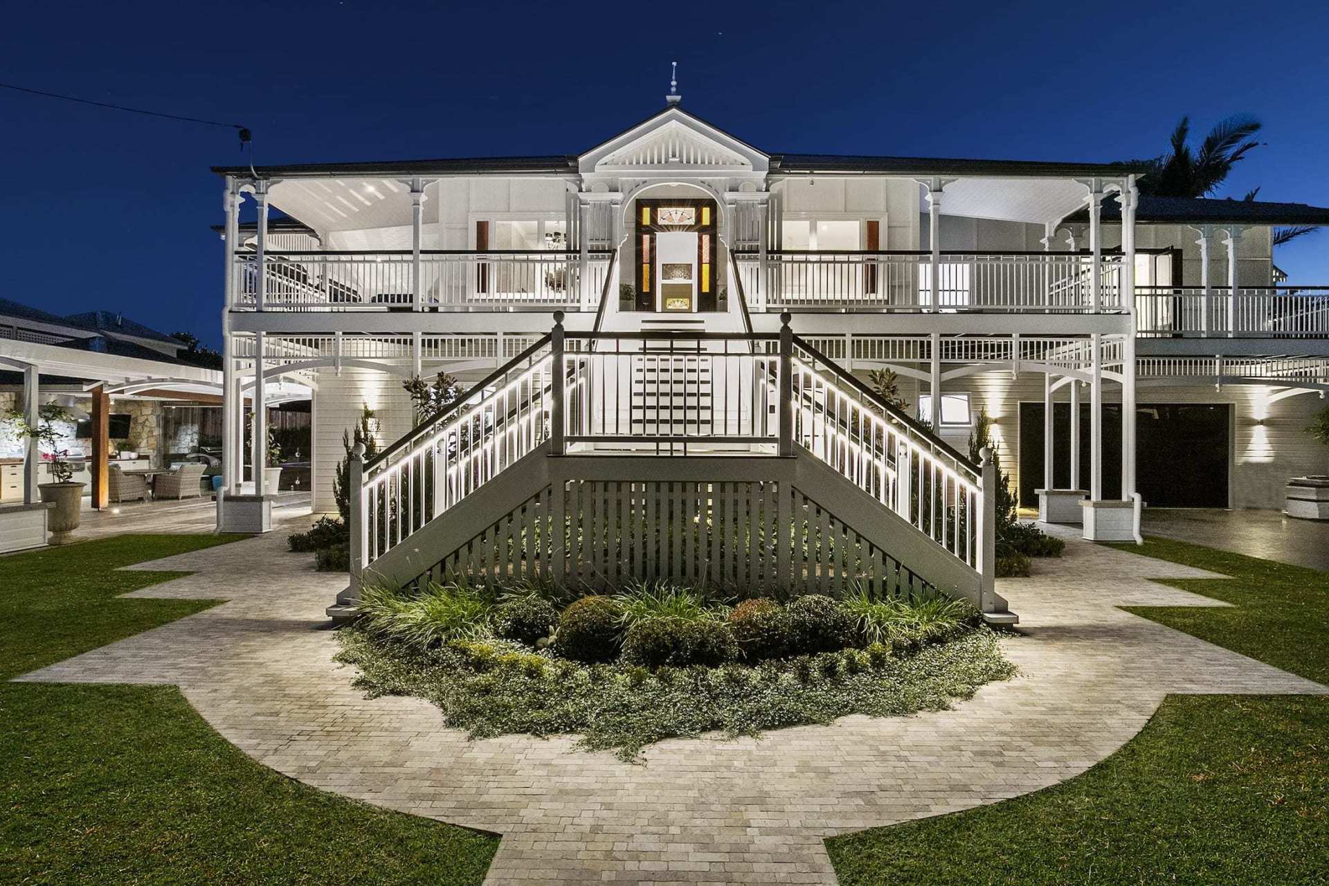 A large white house with stairs leading up to it at night.