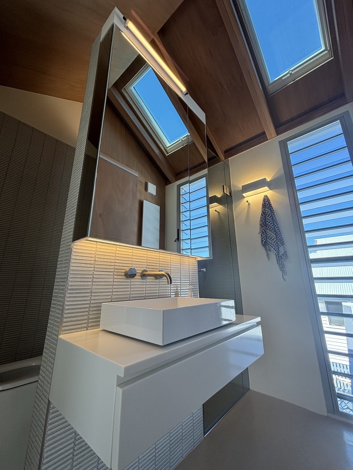 A bathroom with a sink , mirror and skylight.