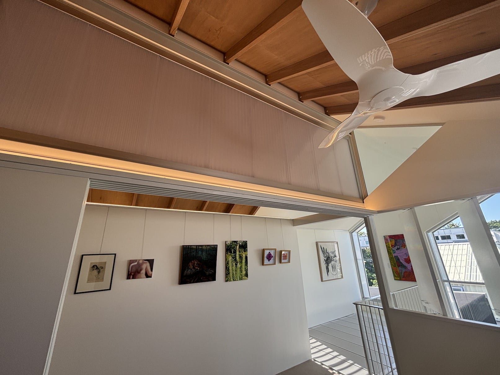 A room with a ceiling fan and paintings on the wall
