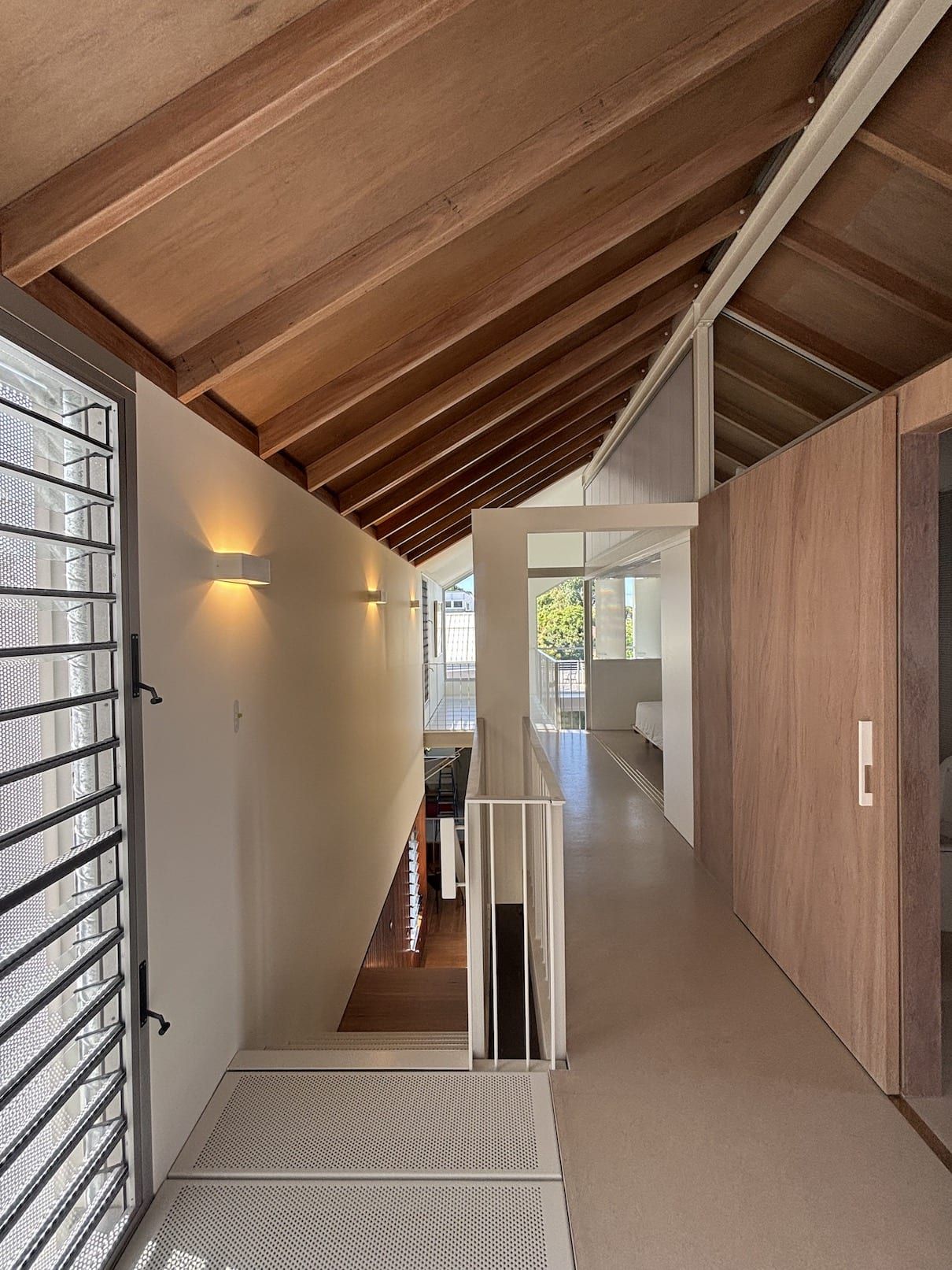A hallway in a house with a wooden ceiling and stairs