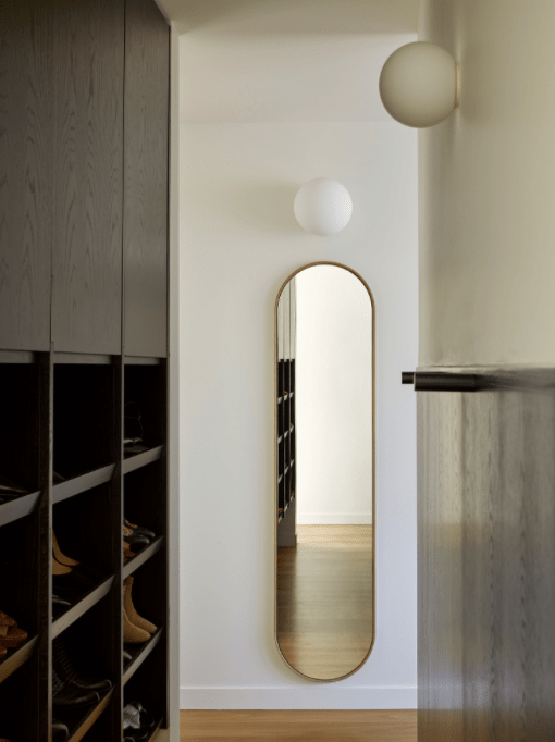 A full length mirror is hanging on a wall in a hallway