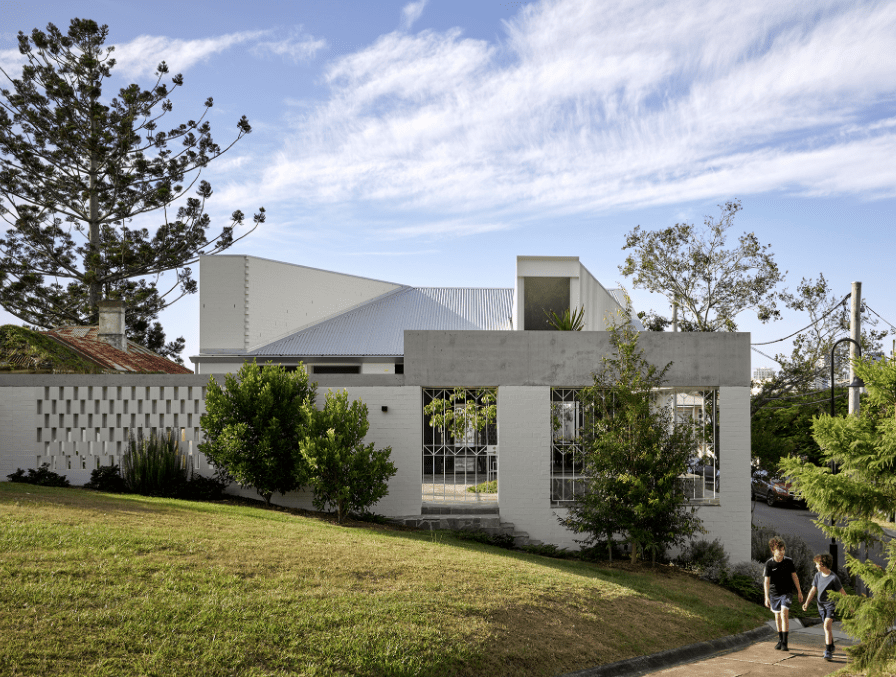 A couple of people are walking in front of a white house.