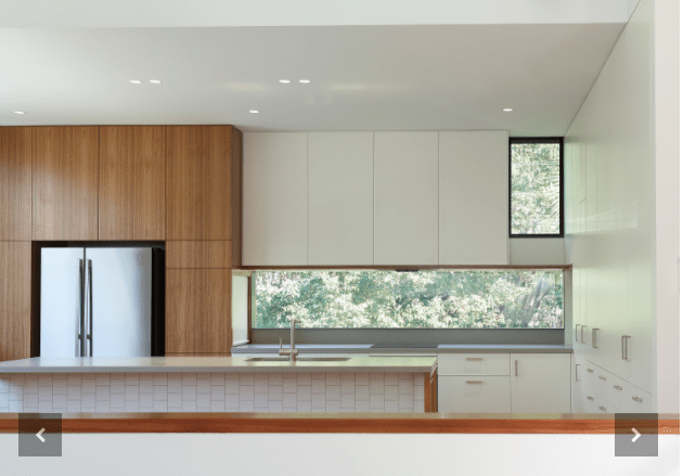 A kitchen with white cabinets and a stainless steel refrigerator