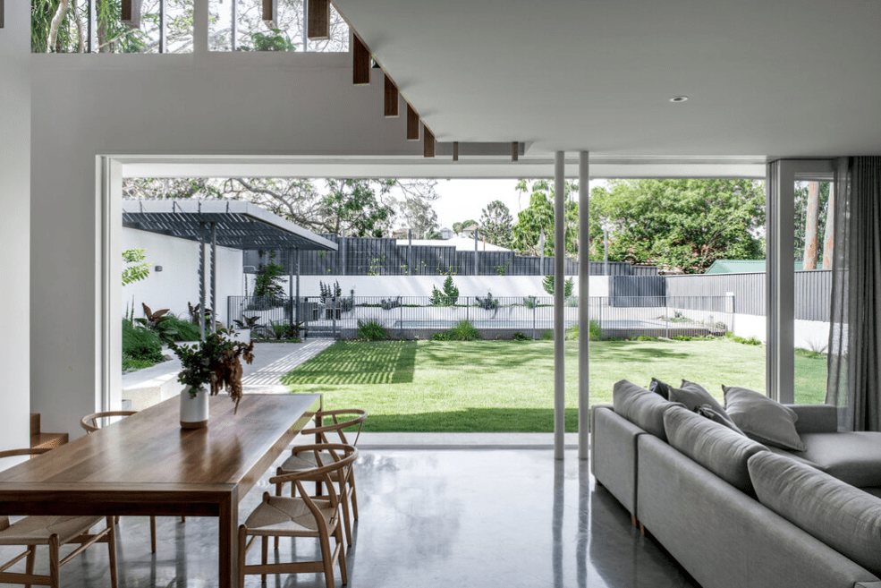 A living room with a couch , table , chairs and sliding glass doors leading to a backyard.