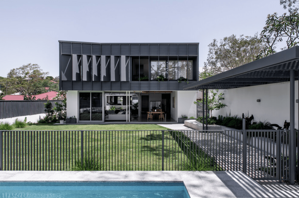A black and white house with a swimming pool in front of it.