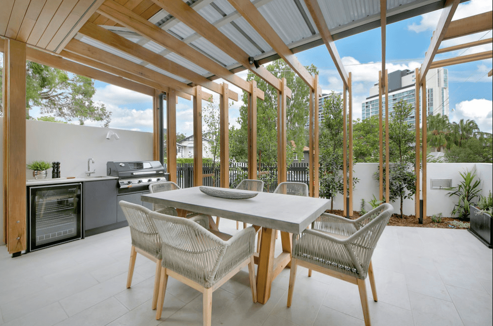 A patio with a table and chairs and a grill.