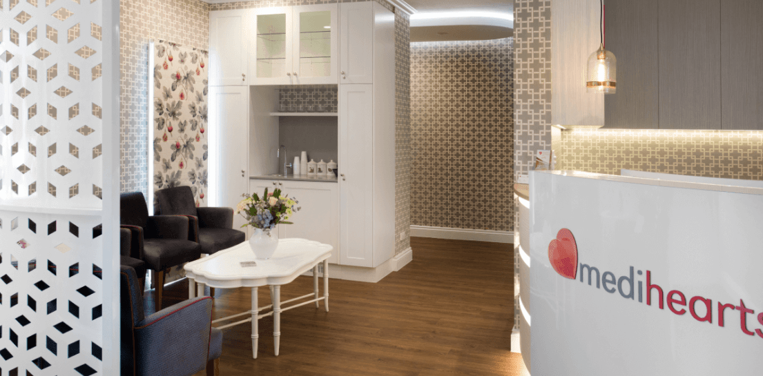 A waiting room with a table , chairs , and a desk.
