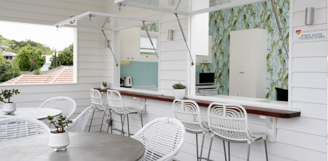 A patio with tables and chairs and a kitchen in the background.