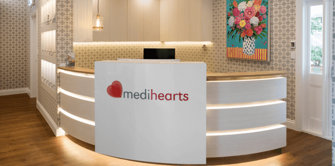 A white reception desk in a room with a painting on the wall.