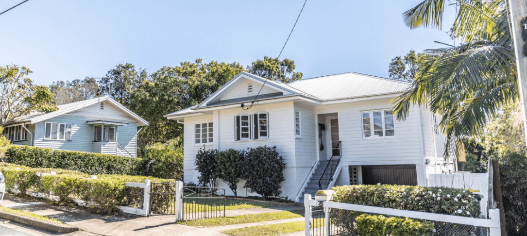 A row of white houses sitting next to each other on a sunny day.
