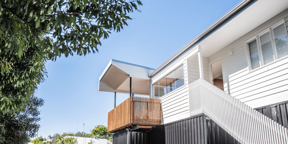 A white house with a balcony and stairs on a sunny day.