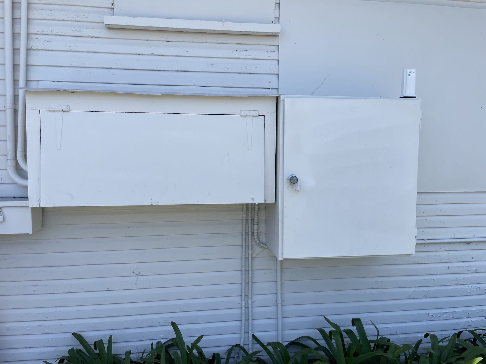 A white box is sitting on the side of a white building.