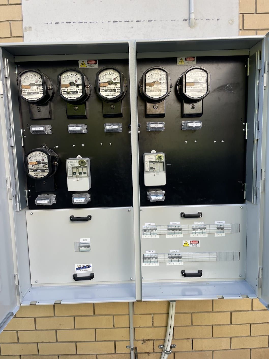 Two electrical boxes on a brick wall with meters on them
